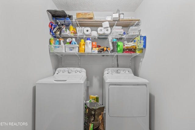 laundry area with independent washer and dryer and a textured ceiling