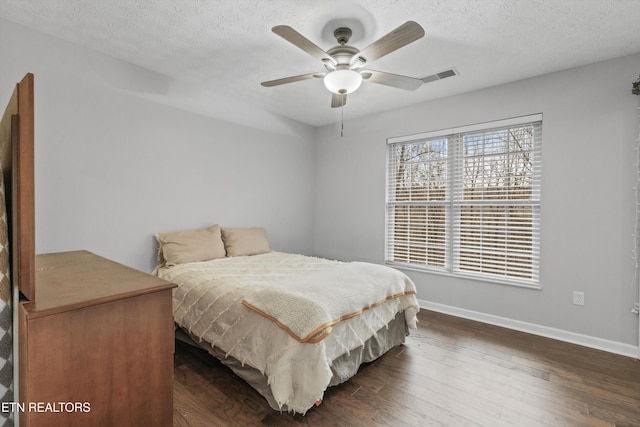 bedroom with a textured ceiling, ceiling fan, and dark wood-type flooring