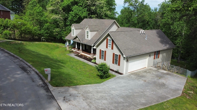 exterior space featuring covered porch, driveway, roof with shingles, fence, and a front lawn