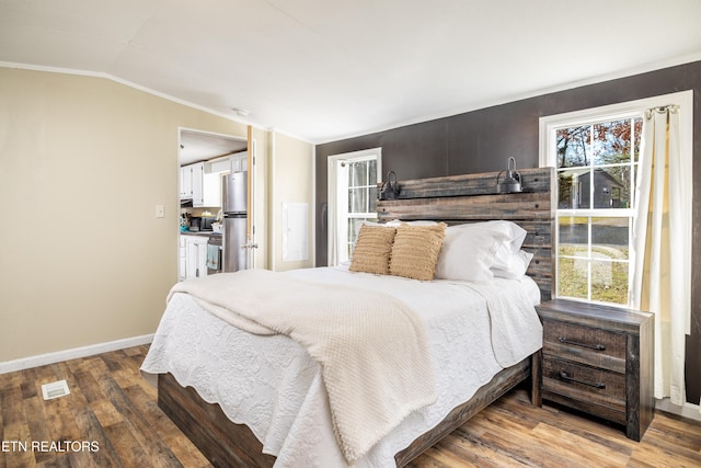 bedroom with multiple windows, stainless steel fridge, wood-type flooring, and vaulted ceiling