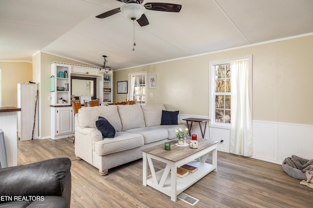 living room with wood-type flooring, vaulted ceiling, ceiling fan, and crown molding