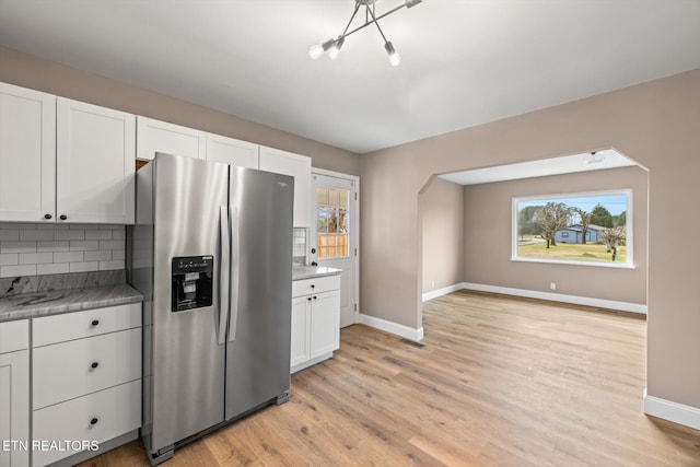 kitchen with stainless steel fridge with ice dispenser, light wood-type flooring, white cabinetry, and a wealth of natural light