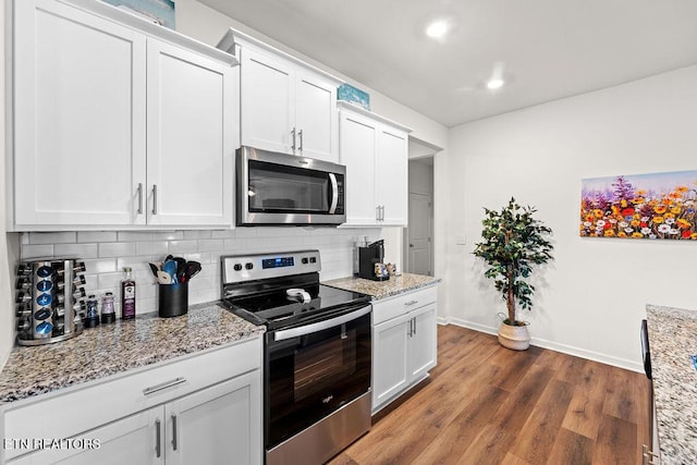 kitchen with light stone countertops, appliances with stainless steel finishes, backsplash, dark hardwood / wood-style floors, and white cabinetry