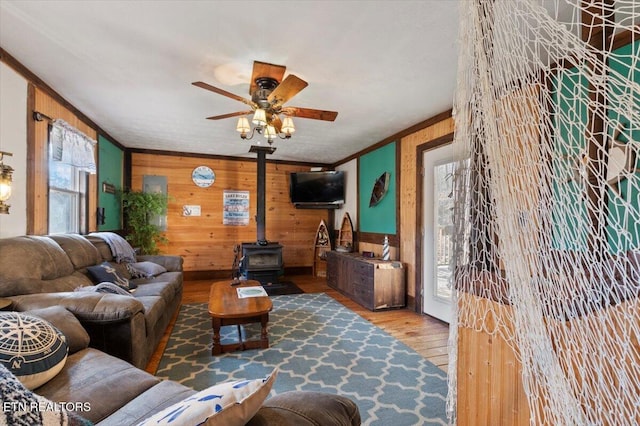 291 Marina Ln, Lafollette, TN 37766 - living room featuring a wood stove, ceiling fan, ornamental molding, wood walls, and hardwood / wood-style flooring
