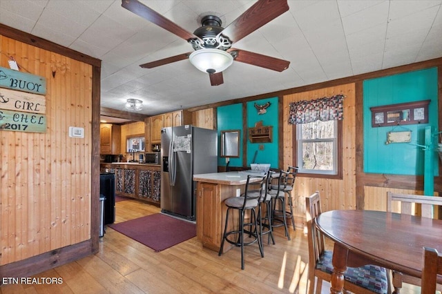 291 Marina Ln, Lafollette, TN 37766 - kitchen with a kitchen bar, ceiling fan, wooden walls, stainless steel fridge with ice dispenser, and light hardwood / wood-style floors
