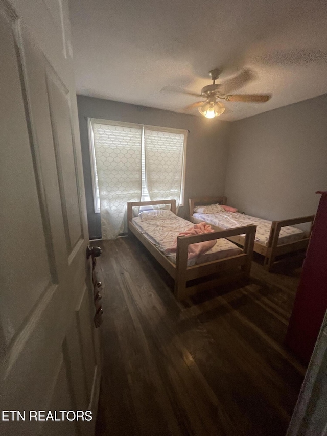 bedroom featuring a textured ceiling, dark hardwood / wood-style floors, and ceiling fan