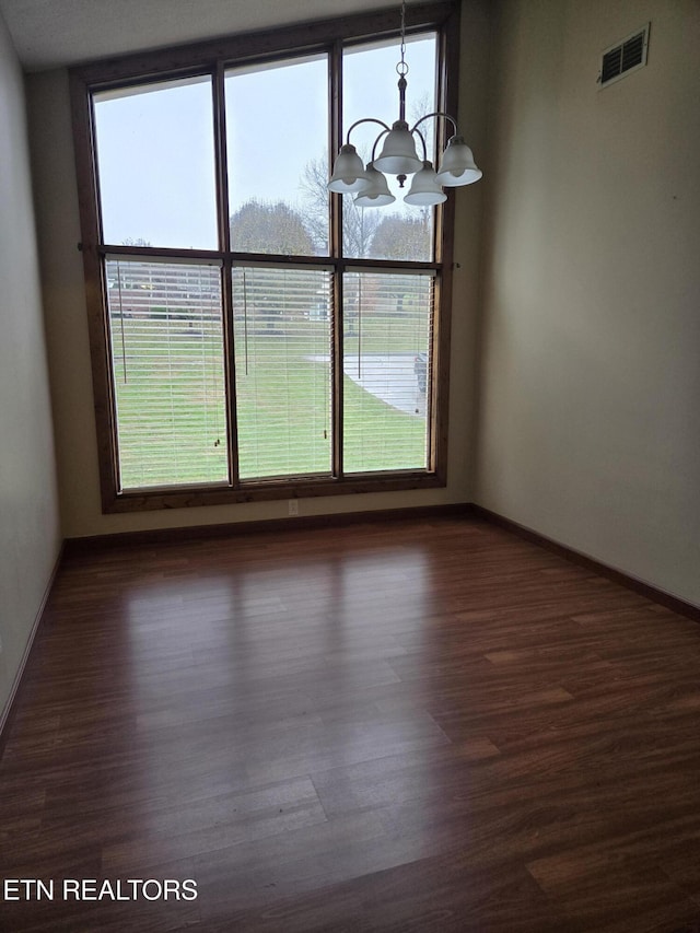 unfurnished dining area featuring an inviting chandelier, a healthy amount of sunlight, visible vents, and dark wood-type flooring