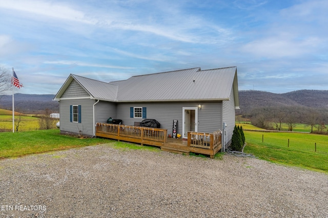 view of front of home featuring a deck with mountain view and a front yard