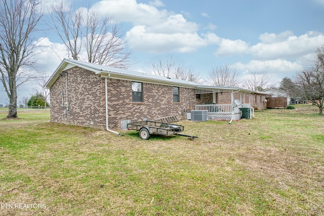 rear view of property with a lawn, a deck, and central air condition unit