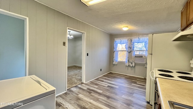 kitchen featuring light hardwood / wood-style flooring, white range with electric stovetop, washer / clothes dryer, wood walls, and a textured ceiling