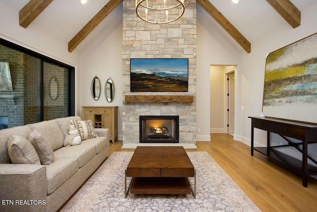 living room featuring light wood-type flooring, beam ceiling, high vaulted ceiling, a notable chandelier, and a fireplace