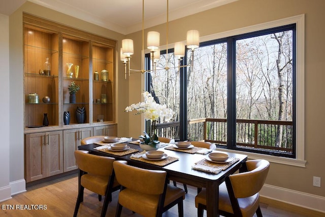 dining room with light wood-type flooring and crown molding