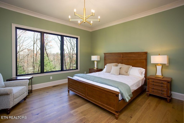 bedroom with wood-type flooring, an inviting chandelier, and crown molding