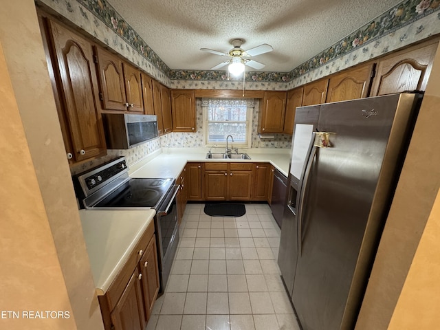 kitchen featuring light tile patterned flooring, sink, a textured ceiling, appliances with stainless steel finishes, and ceiling fan