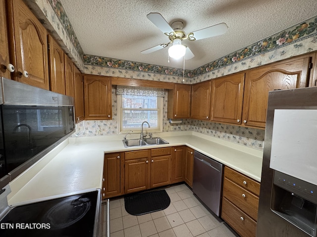 kitchen featuring sink, light tile patterned floors, ceiling fan, stainless steel appliances, and a textured ceiling