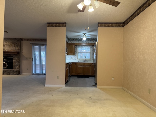 kitchen featuring sink, a textured ceiling, stainless steel refrigerator, light colored carpet, and a fireplace