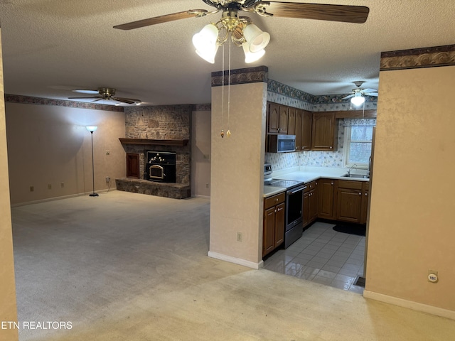 kitchen featuring sink, stainless steel appliances, a textured ceiling, light colored carpet, and kitchen peninsula