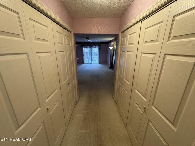 hall with carpet flooring and a textured ceiling