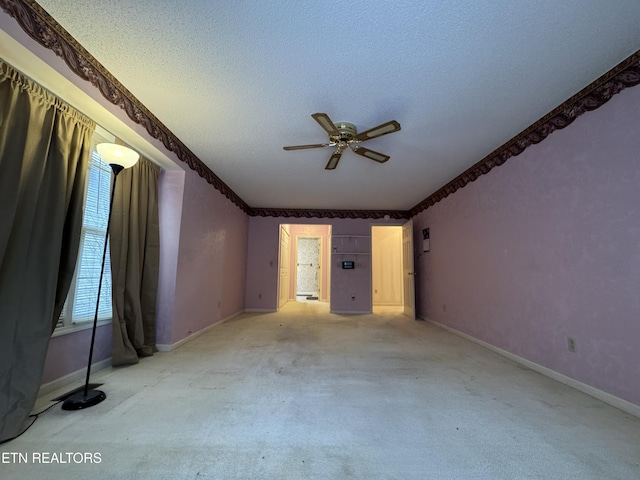 empty room with ceiling fan, light carpet, and a textured ceiling