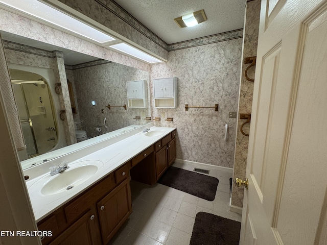 bathroom featuring toilet, vanity, a textured ceiling, and walk in shower