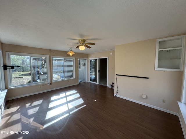 empty room featuring ceiling fan, a textured ceiling, built in features, and dark hardwood / wood-style flooring