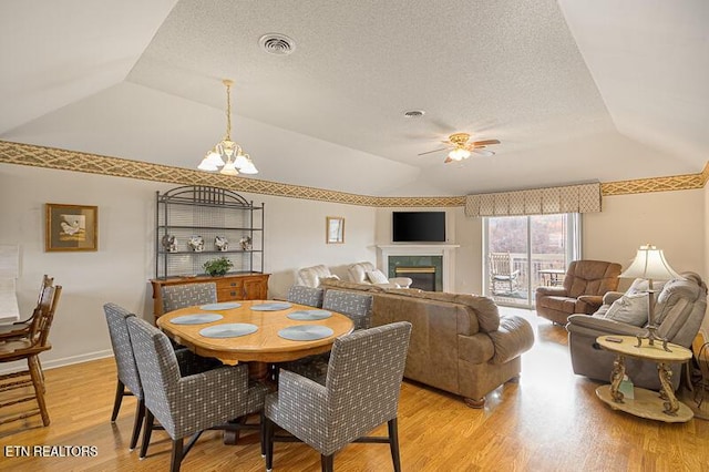 dining area with ceiling fan with notable chandelier, vaulted ceiling, and light hardwood / wood-style flooring