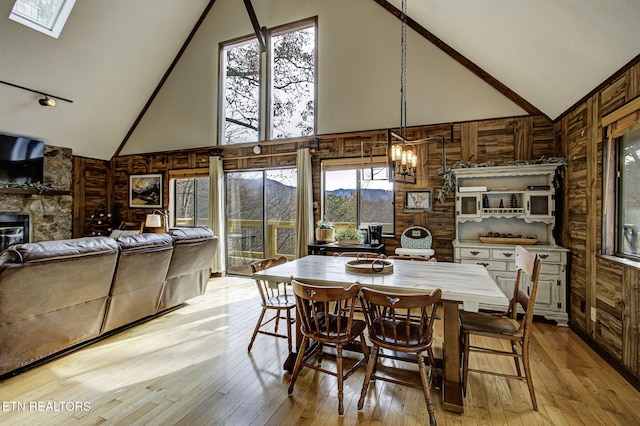 dining area featuring high vaulted ceiling, plenty of natural light, and wood walls