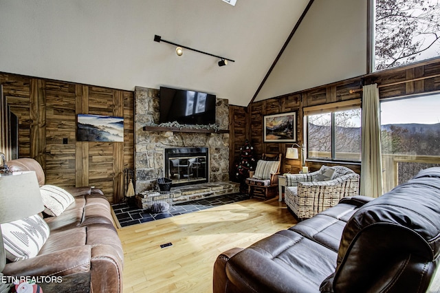 living room with hardwood / wood-style flooring, wooden walls, a fireplace, and high vaulted ceiling