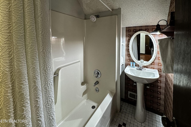 bathroom with tile patterned flooring, shower / bath combo with shower curtain, and a textured ceiling