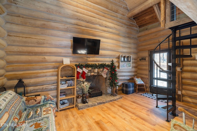 living room with log walls, hardwood / wood-style floors, vaulted ceiling, and a stone fireplace