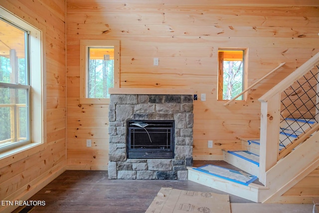 unfurnished living room featuring wooden walls, a wealth of natural light, and a fireplace