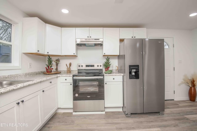 kitchen with light stone countertops, white cabinetry, sink, light hardwood / wood-style floors, and appliances with stainless steel finishes