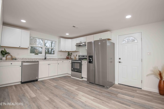 kitchen with appliances with stainless steel finishes, light hardwood / wood-style floors, white cabinetry, and sink