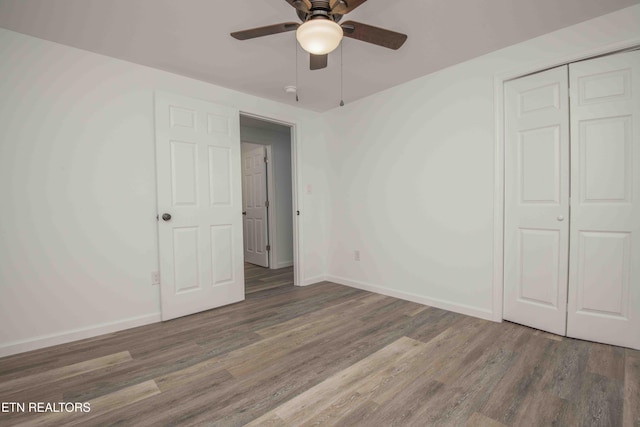 unfurnished bedroom featuring ceiling fan, dark wood-type flooring, and a closet