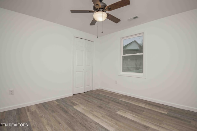 unfurnished bedroom with hardwood / wood-style flooring, ceiling fan, and a closet