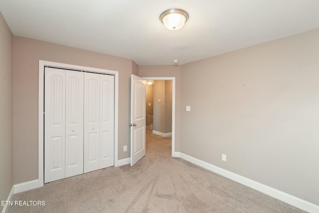 unfurnished bedroom with light carpet and a closet