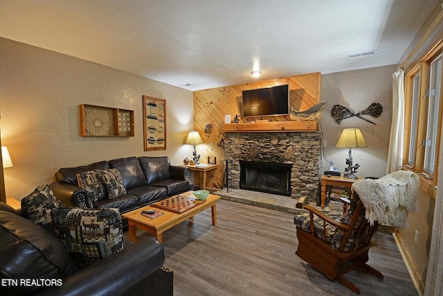 living room with hardwood / wood-style floors, wood walls, and a fireplace