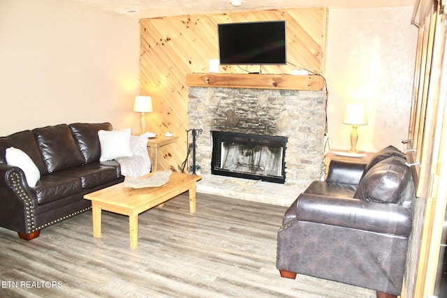 living room featuring wood walls, a fireplace, and wood finished floors