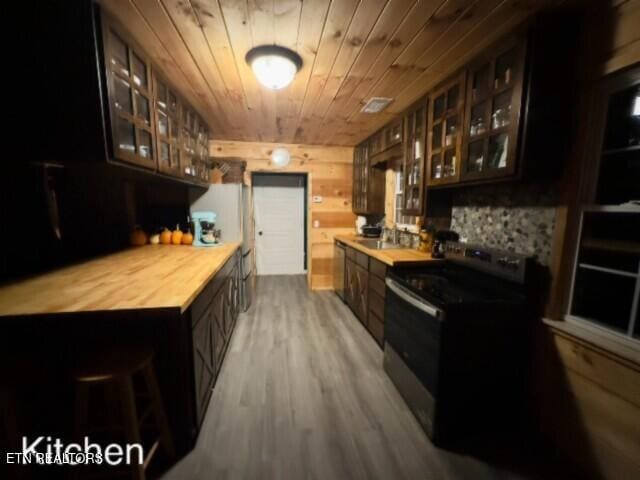 bar featuring wood walls, wood-type flooring, sink, black range with electric cooktop, and wood ceiling