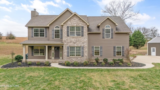 view of front of property featuring a porch, brick siding, a shingled roof, a chimney, and a front yard