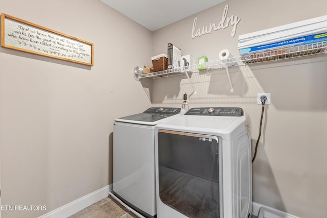 washroom featuring washing machine and dryer, laundry area, and baseboards