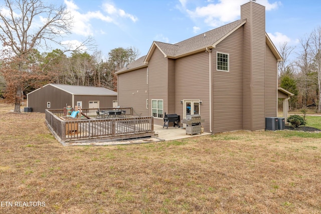 rear view of house featuring a chimney, central AC unit, a deck, and a lawn