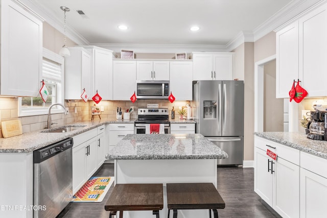 kitchen with appliances with stainless steel finishes, white cabinets, a sink, and ornamental molding