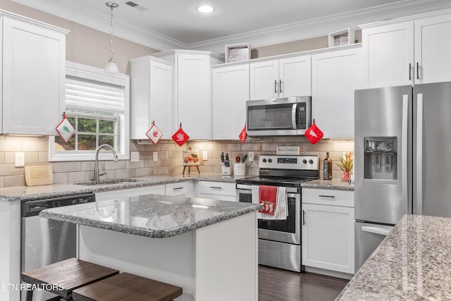 kitchen featuring crown molding, stainless steel appliances, decorative backsplash, white cabinetry, and a sink