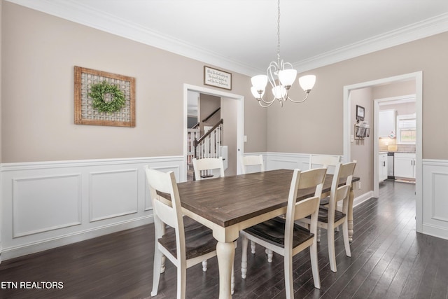 dining space with dark wood-style flooring, a wainscoted wall, ornamental molding, a chandelier, and stairs