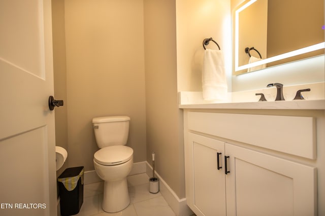 bathroom with toilet, vanity, and tile patterned floors