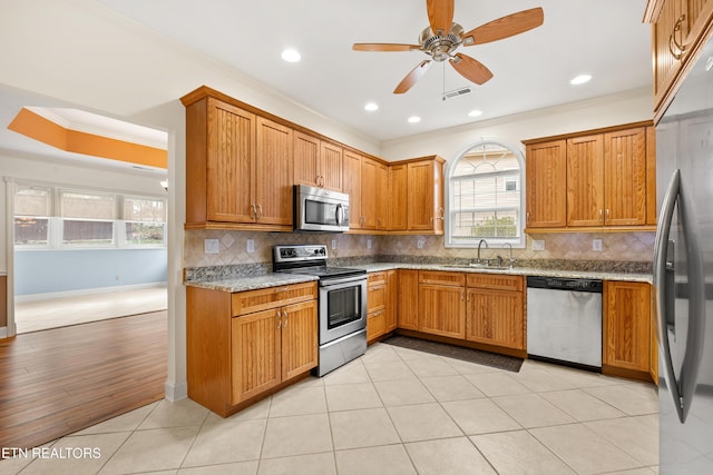 kitchen with sink, stainless steel appliances, backsplash, light hardwood / wood-style floors, and ornamental molding