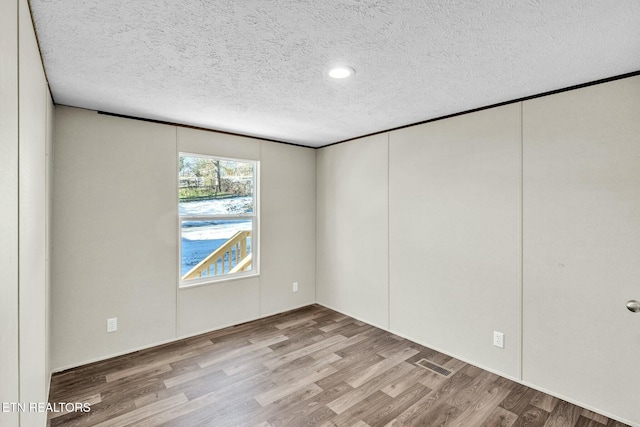 spare room with a textured ceiling and light hardwood / wood-style flooring