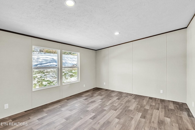 spare room with crown molding, a textured ceiling, and light hardwood / wood-style flooring