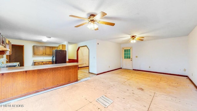 kitchen with kitchen peninsula, ceiling fan, black refrigerator, and sink